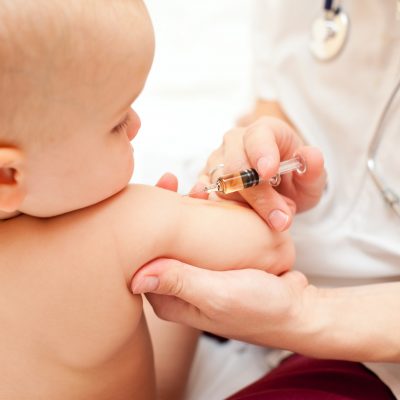 Doctor giving a child an intramuscular injection in arm